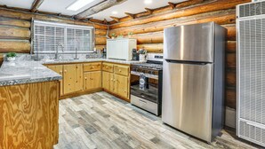A log cabin kitchen with wooden cabinets, a stainless steel refrigerator, and a wood-burning stove. - MTB Base Camp! Rustic Cabin By Mt Laguna Trails (Mount Laguna)