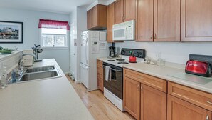 A kitchen with wooden cabinets, a white refrigerator, a microwave, a stove, and a toaster.