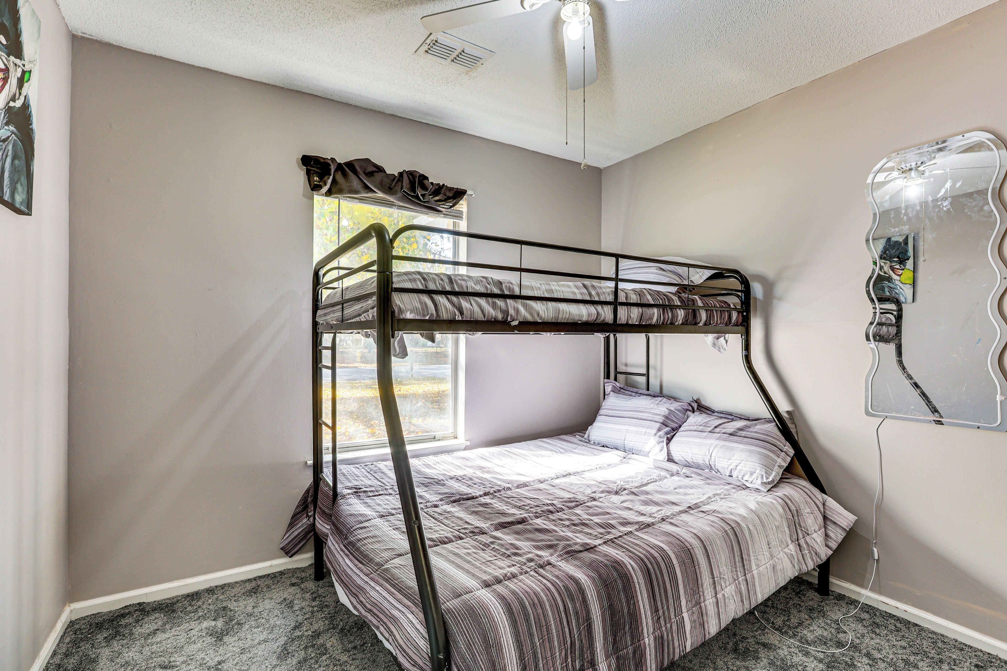 A bunk bed room with a window, a mirror, and a ceiling fan.