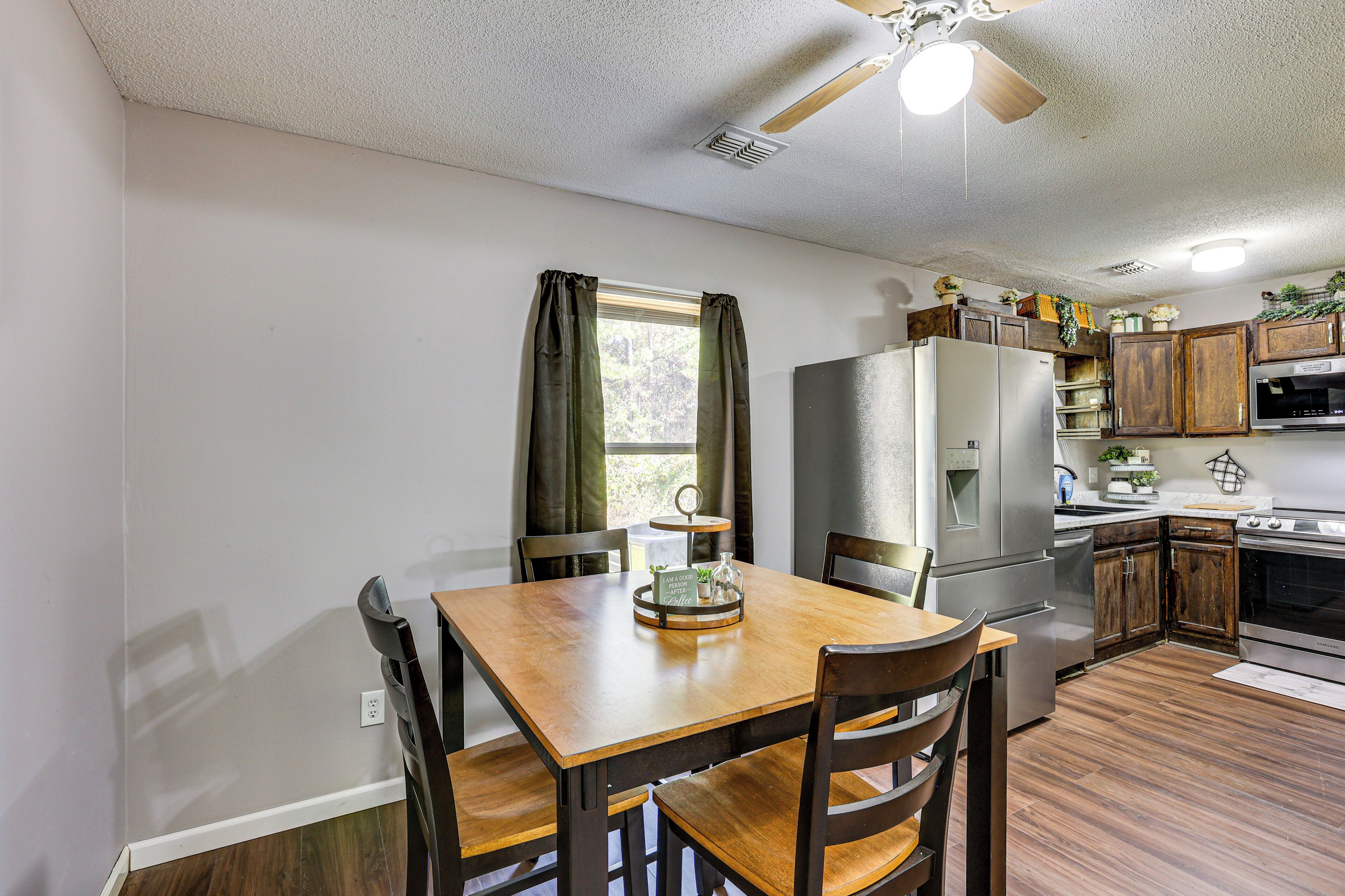A kitchen with a wooden table and chairs, a refrigerator, microwave, and wooden cabinets.