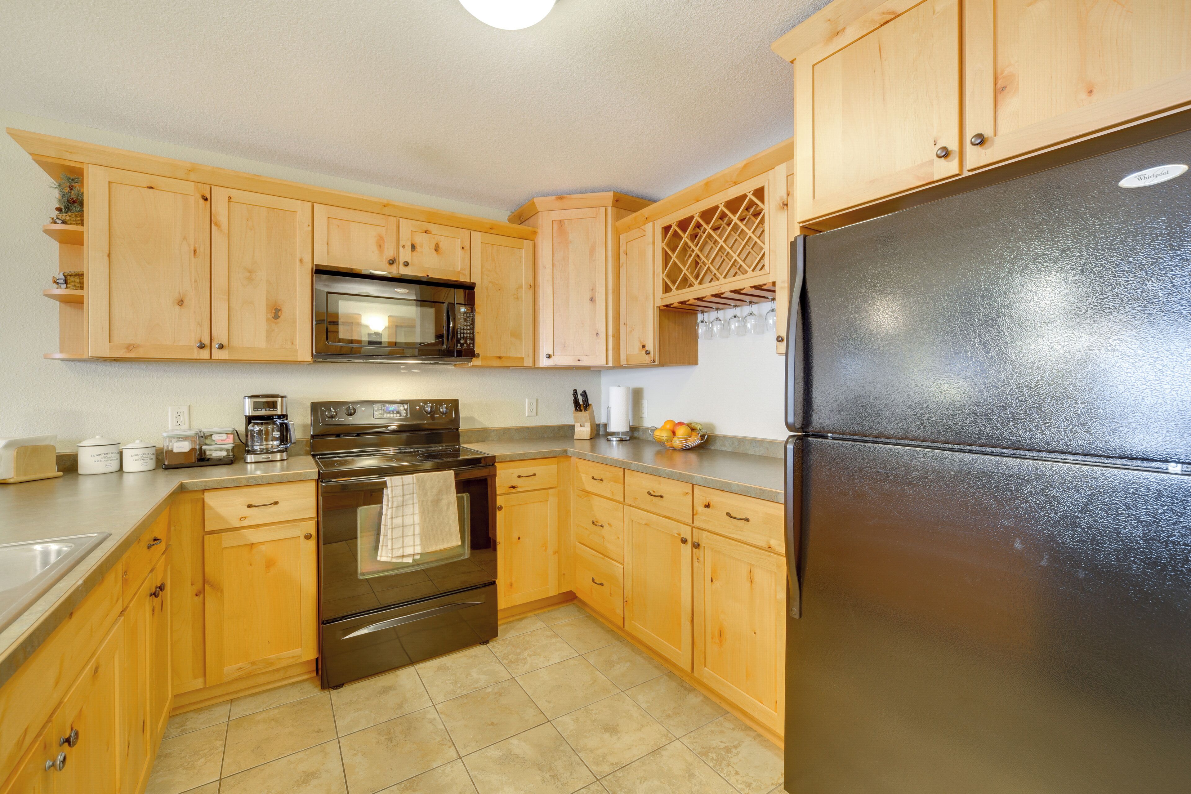 A kitchen with wooden cabinets, stainless steel appliances, and a black refrigerator.