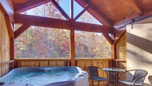 Una terraza de madera con un jacuzzi, dos sillas y una mesa.