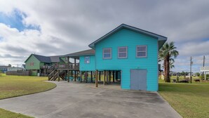 A turquoise building with a covered outdoor area and a concrete pathway. - Steps to Sea! Crystal Beach Home w/ Furnished Deck (Port Bolivar)