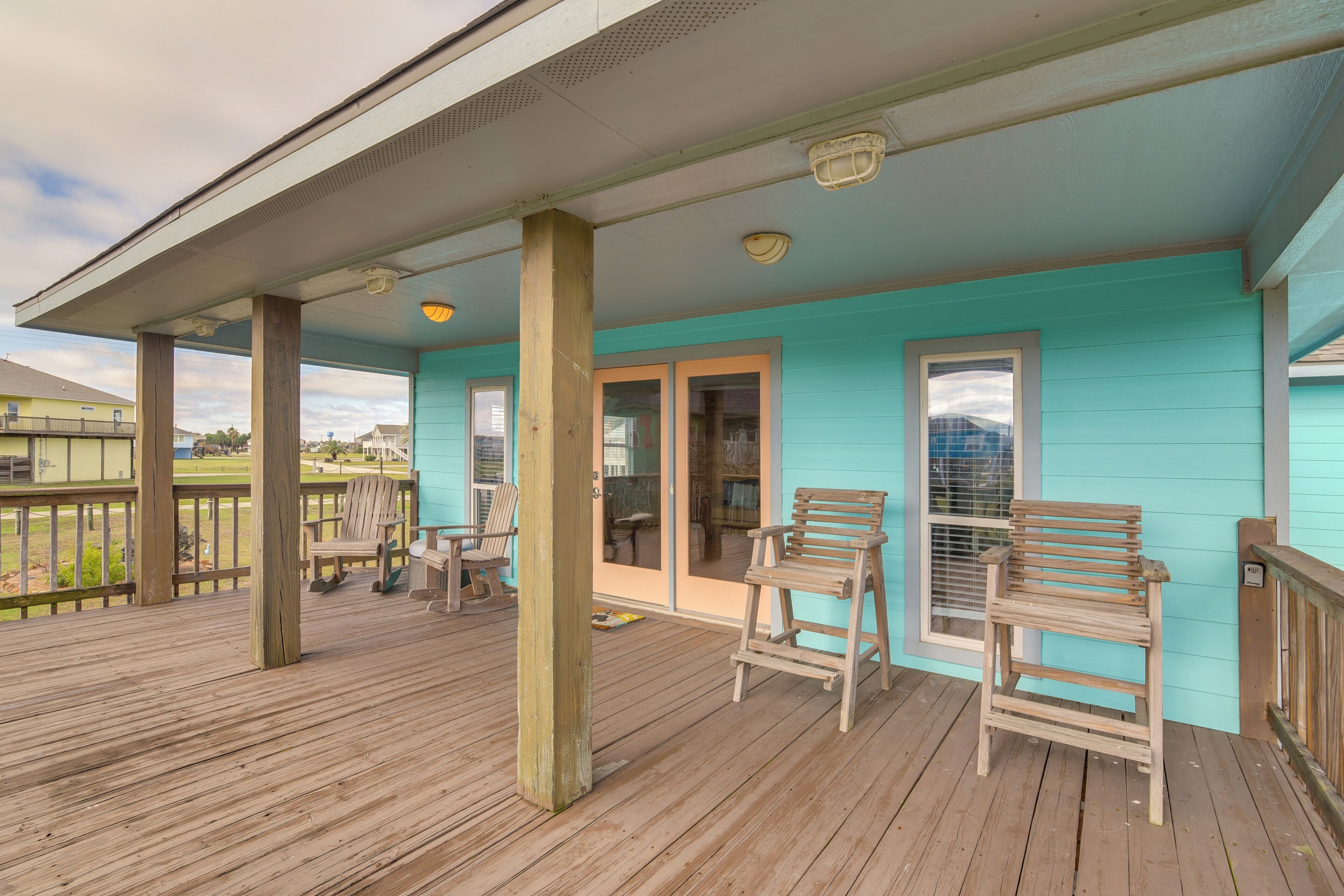 A wooden deck with two wooden chairs, a wooden table, and a door leading to an interior space.