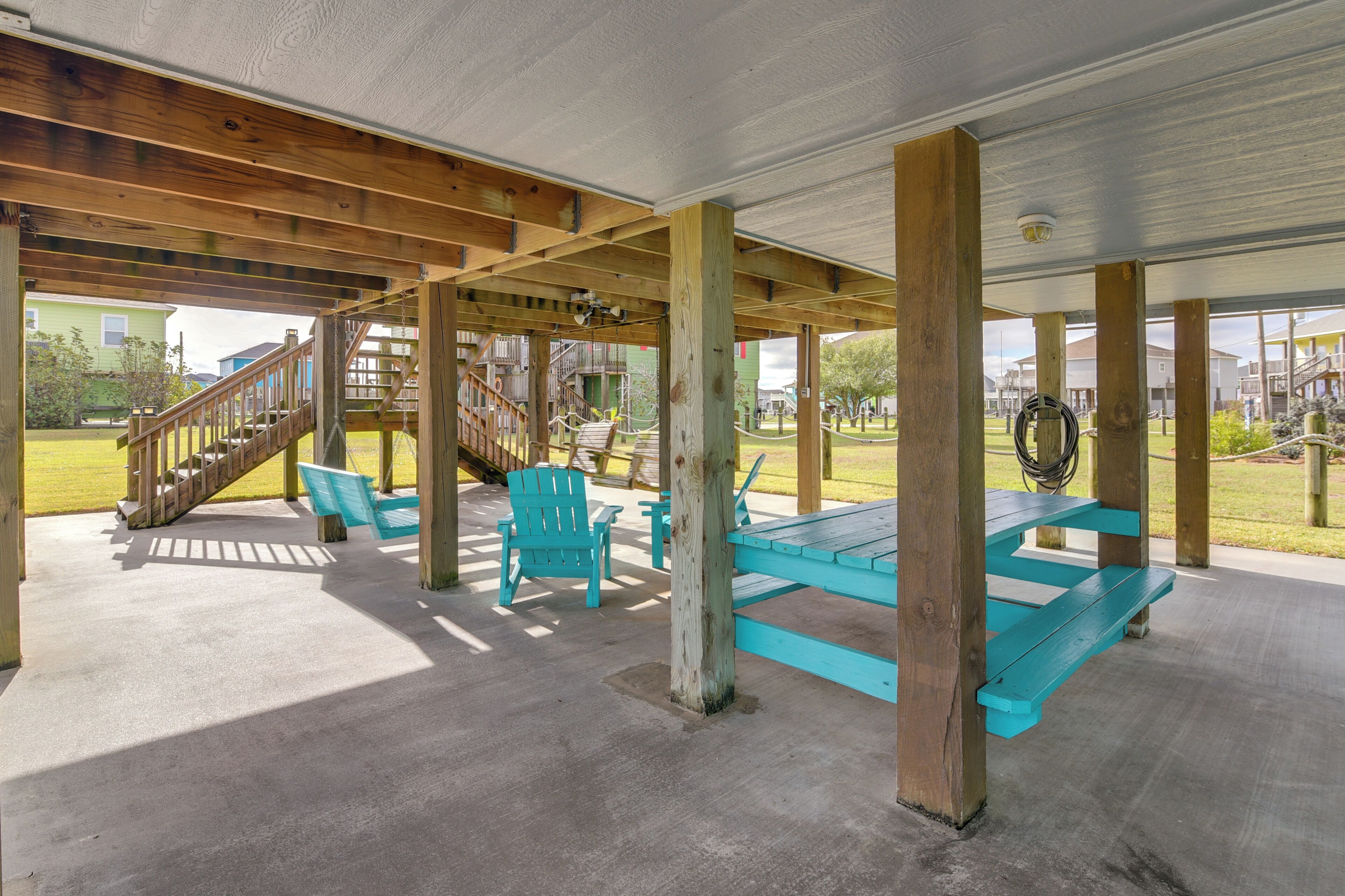 A covered outdoor area with wooden beams, a concrete floor, and turquoise seating.