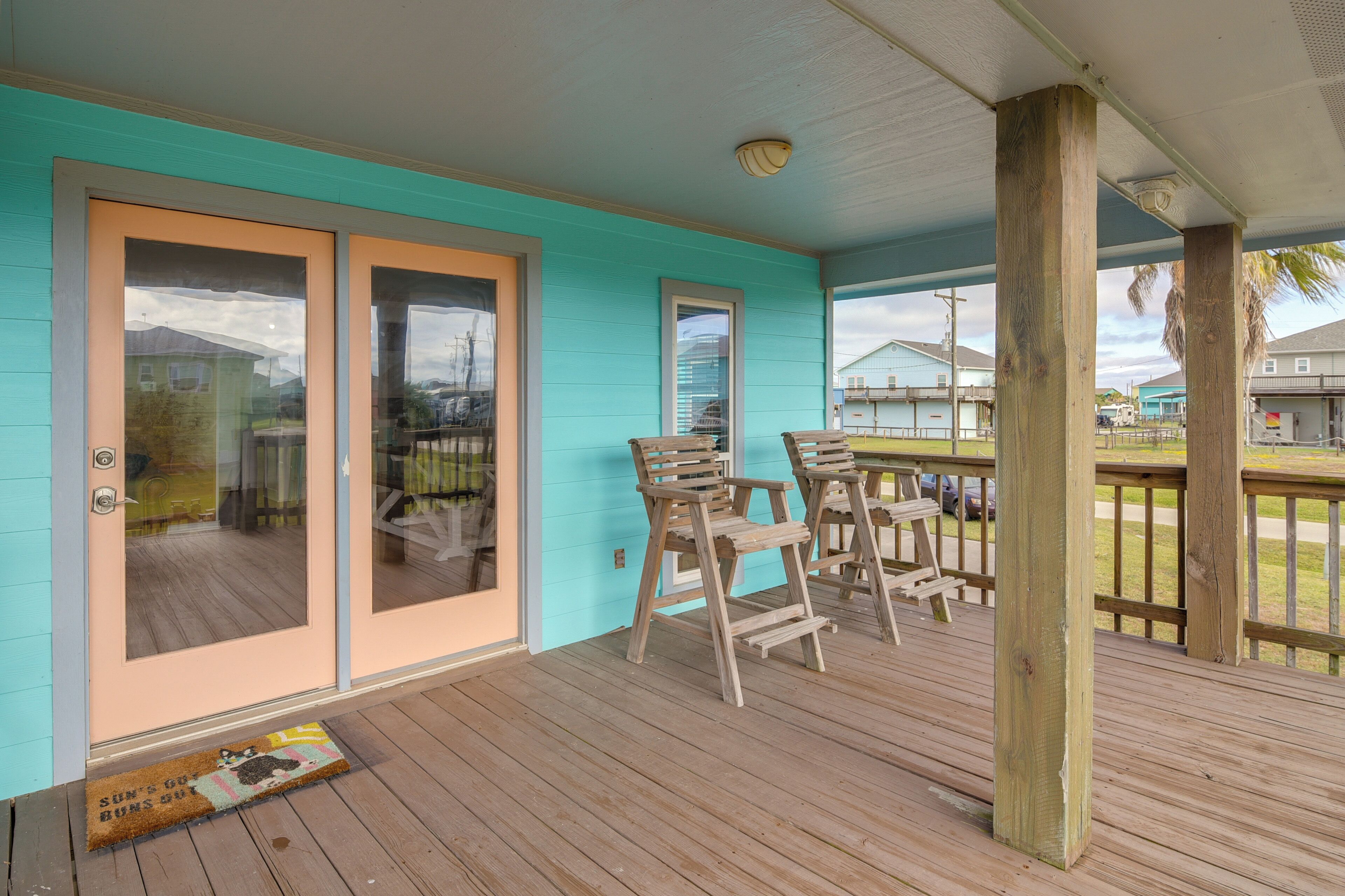 A covered porch with wooden chairs and a wooden table.