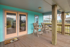 Eine überdachte Veranda mit Holzstühlen, einer Holzterrasse und einer türkisfarbenen Wand.