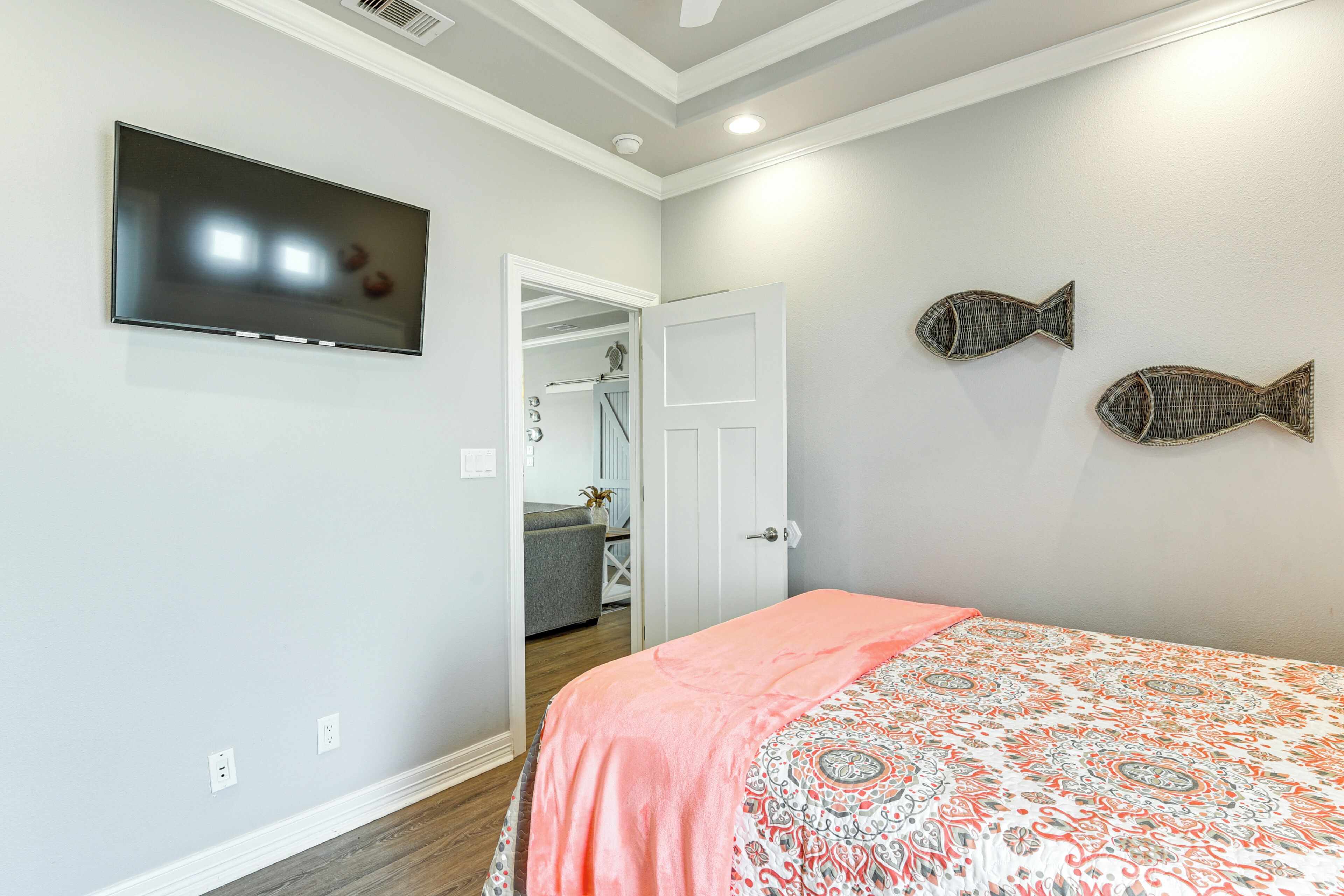 A bedroom with a bed, a television, and two wall-mounted fish decorations.