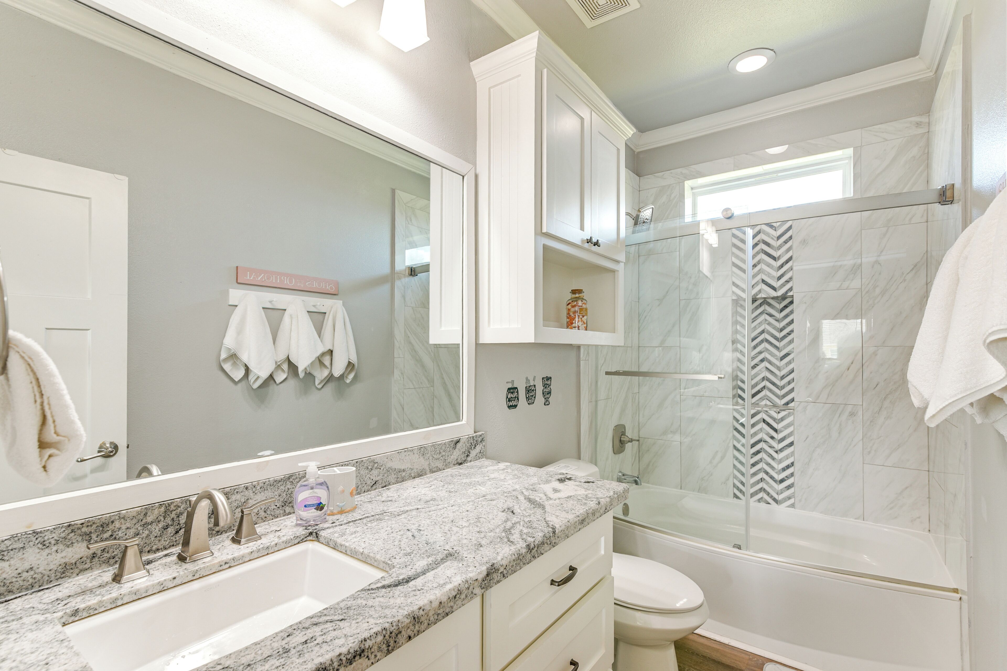 A modern bathroom with a marble sink, a glass-enclosed shower, and a vanity with drawers.
