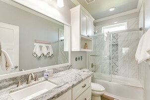 A modern bathroom with a marble sink, a glass-enclosed shower, and a vanity with drawers.
