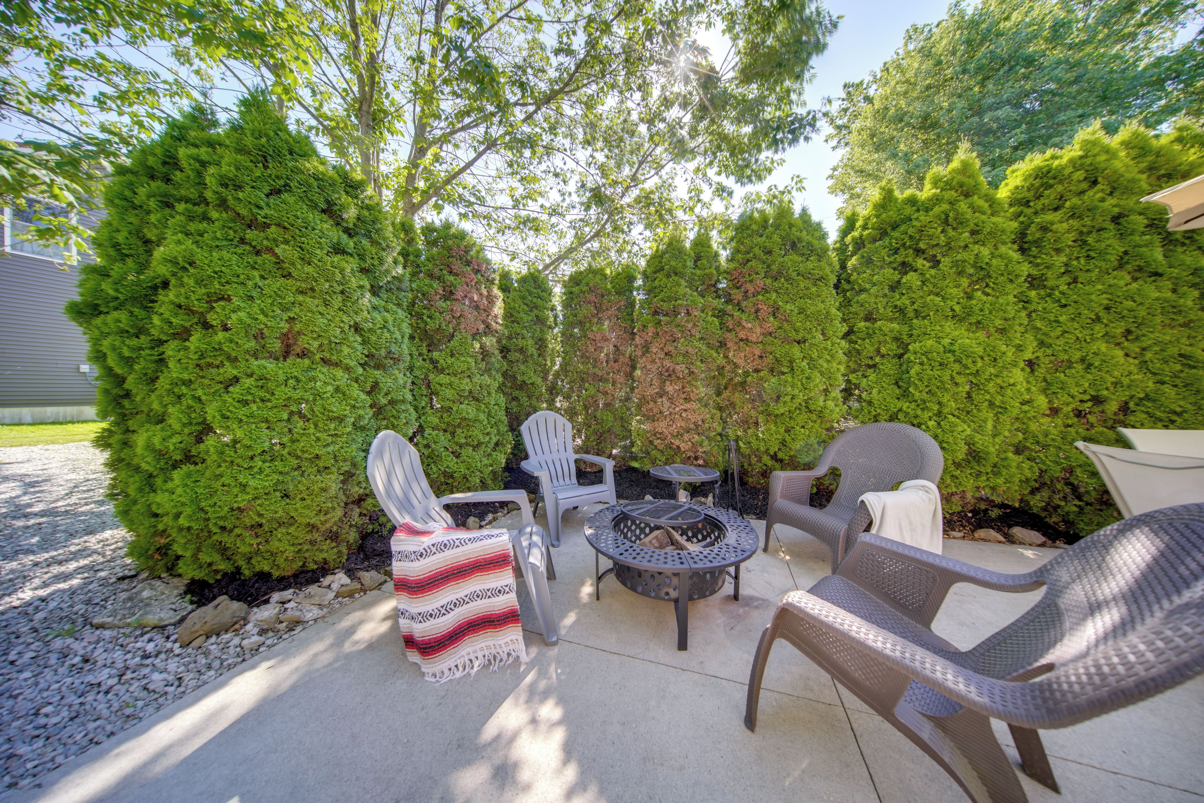 An outdoor patio with a fire pit, wicker furniture, and a stone pathway.