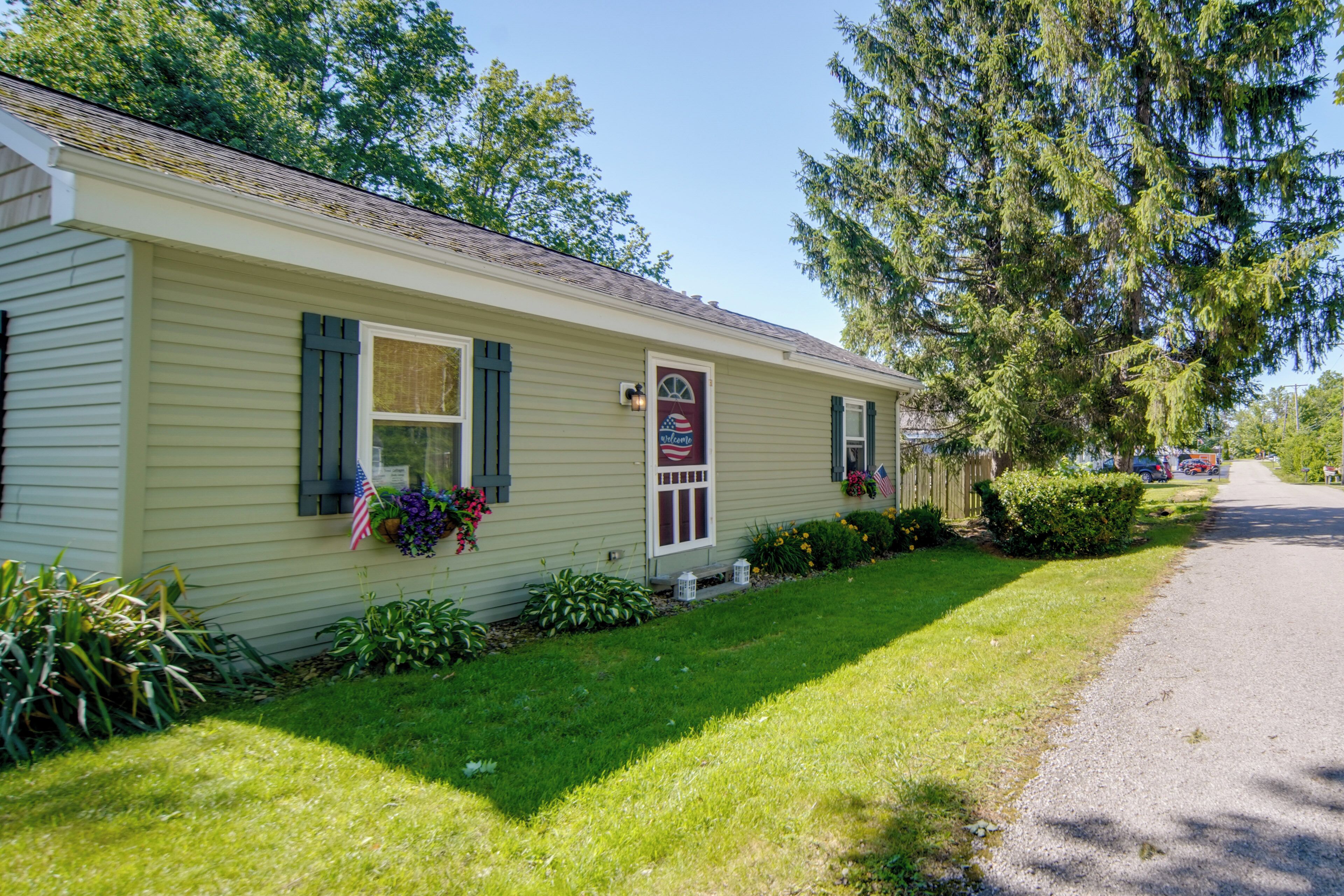 A single-story building with a front porch, a small garden with flowers and plants, and a clear sky.