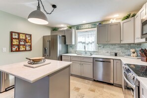 A modern kitchen with a central island, stainless steel appliances, and a decorative backsplash.