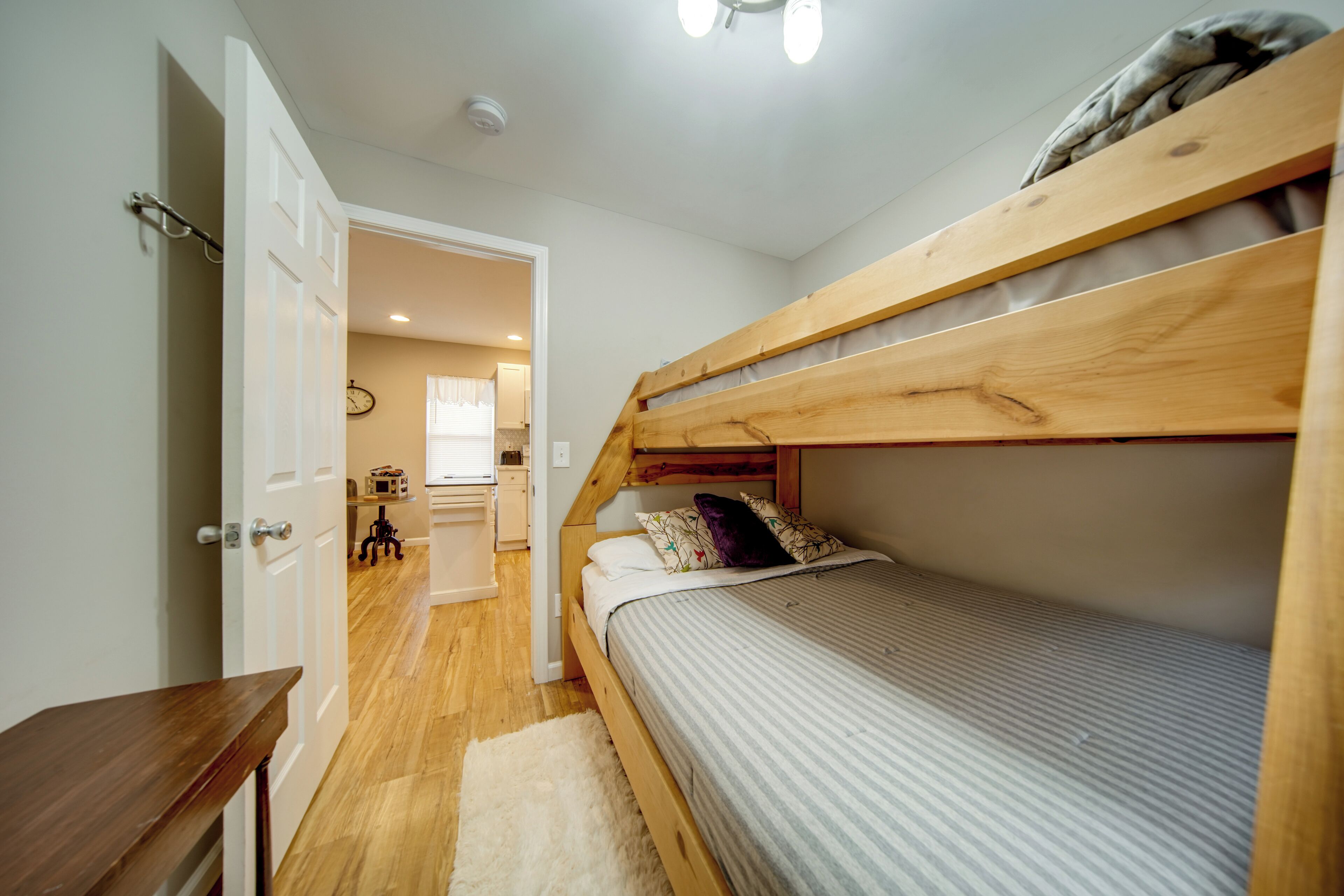 A bunk bed with a wooden headboard, a small bedside table, and a white rug.
