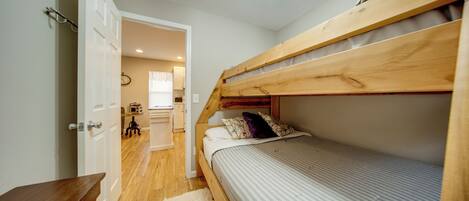 A bunk bed with a wooden headboard, a small bedside table, and a white rug.