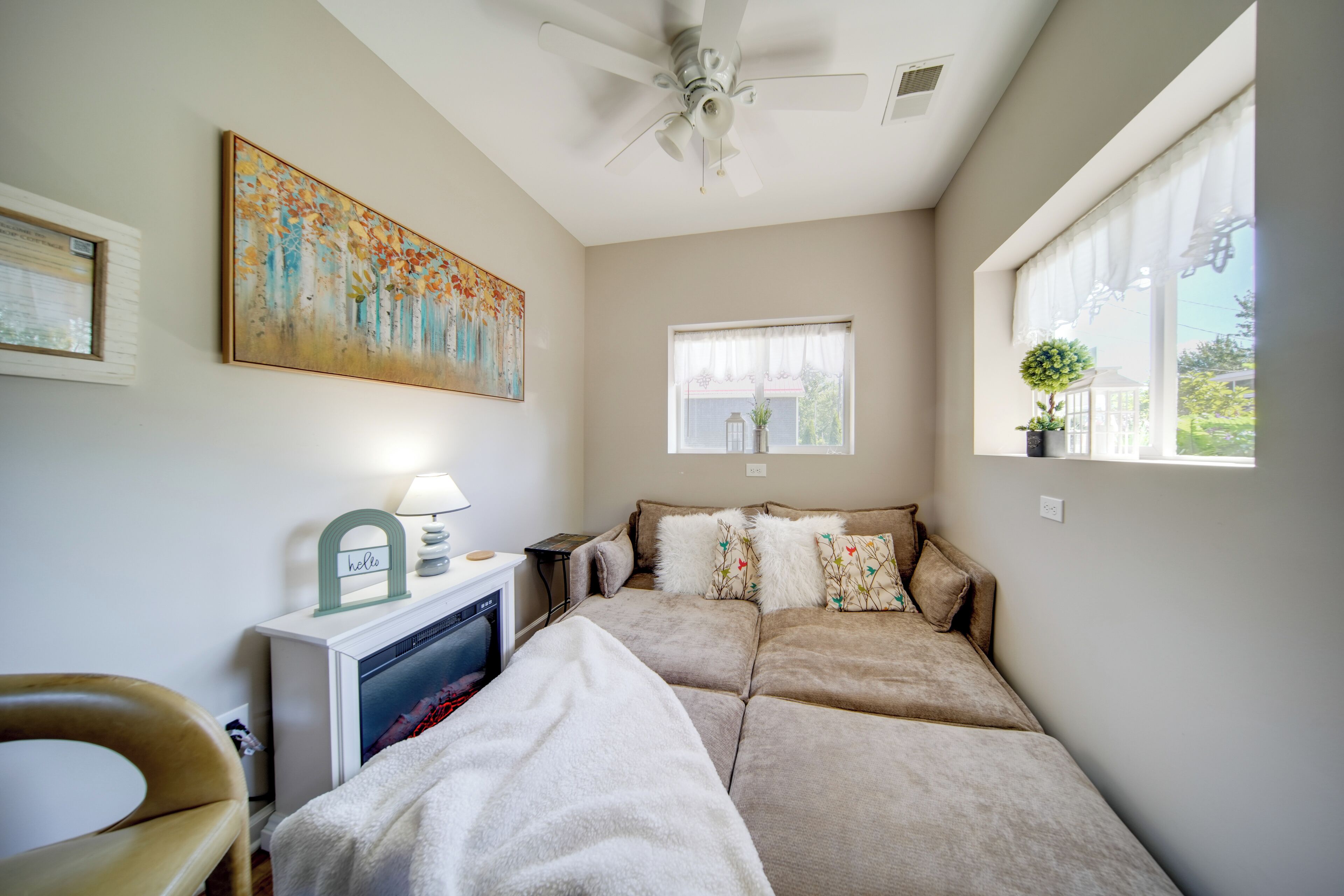A cozy room with a sofa, a TV, a ceiling fan, and a painting on the wall.