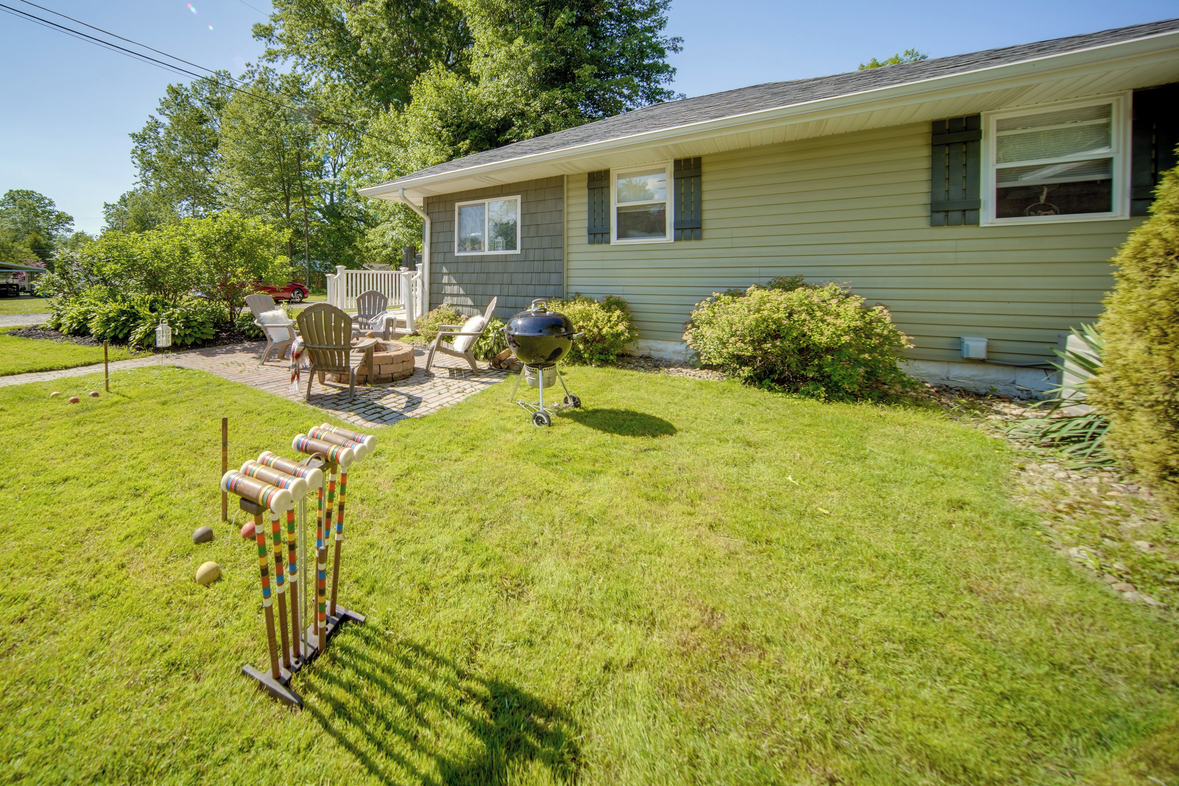 A house with a front yard, a barbecue grill, and outdoor furniture.