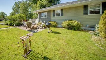 A house with a front yard, a barbecue grill, and outdoor furniture.