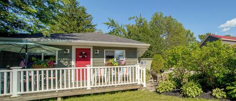 A house with a red door, a white porch railing, and a small deck area.