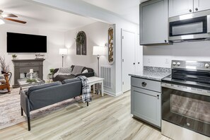A modern kitchen with a built-in oven and microwave, a grey sofa, a fireplace, and a flat-screen TV. - 1 Mi to Lake Hamilton! Newly Remodeled Family Home (Hot Springs)