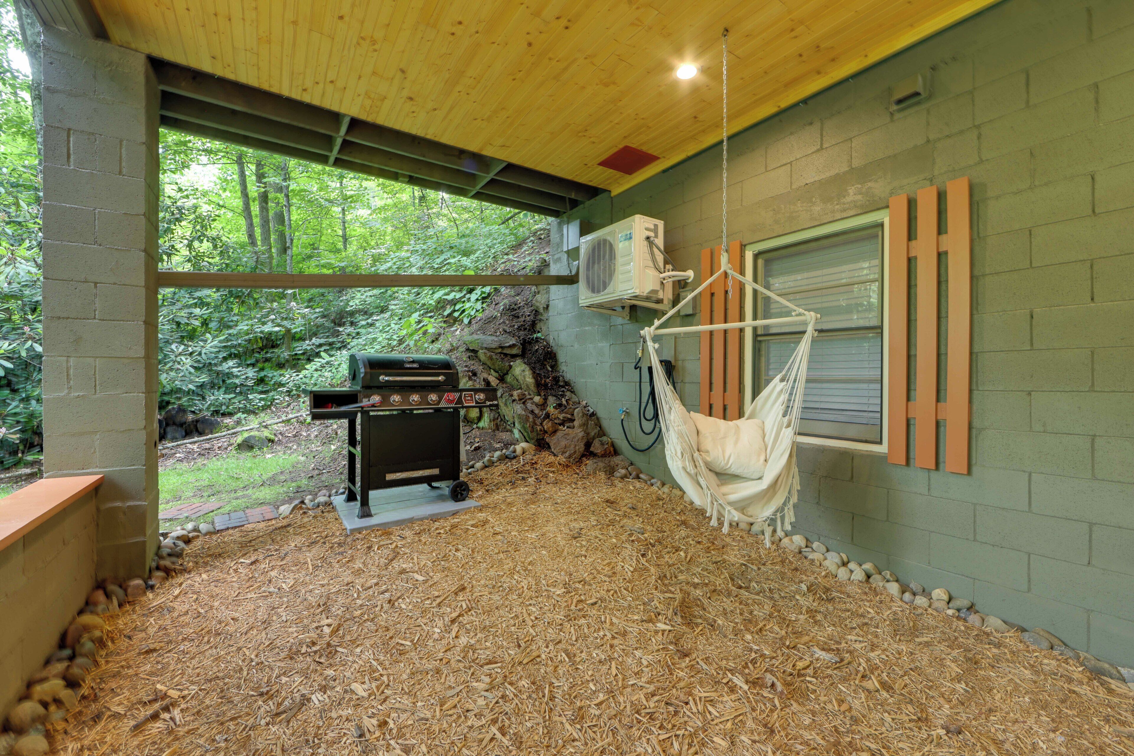Une terrasse extérieure avec un hamac, un barbecue et une vue sur la forêt.
