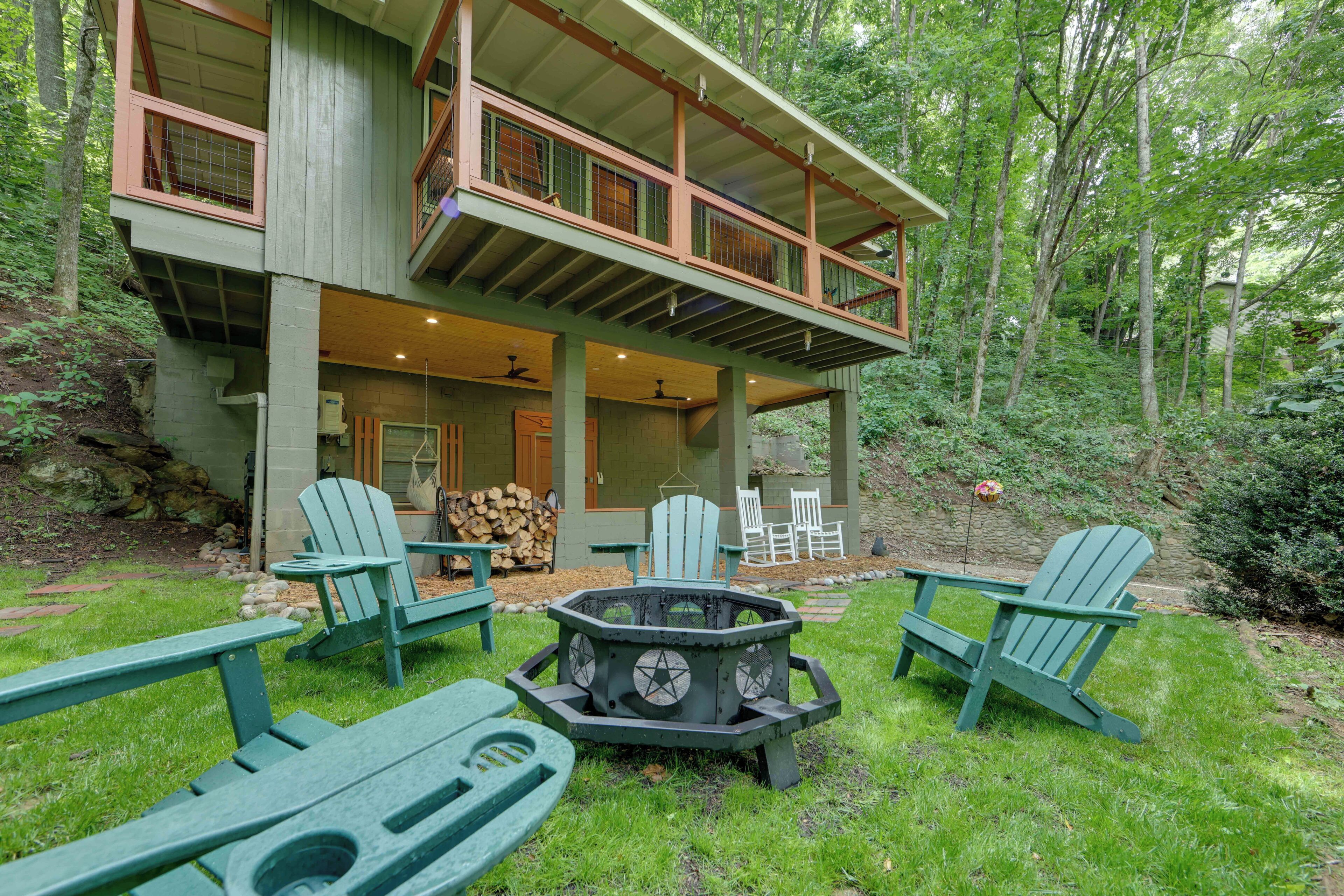 A two-story house with a deck, outdoor seating, and a fire pit.