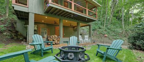 A two-story house with a deck, outdoor seating, and a fire pit.