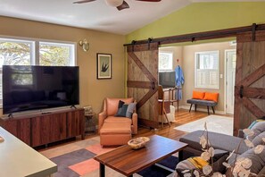 Ein Wohnzimmer mit Fernseher, Ledersofa, Holzschrank und einer Schiebetür im Bauernhausstil.