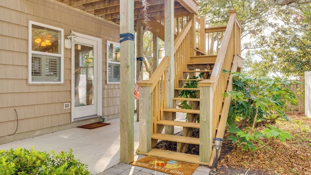 Un escalier en bois menant à une maison avec une porte d’entrée et des fenêtres.