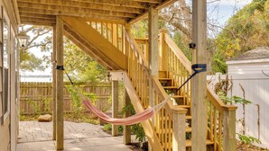 Un escalier en bois avec un hamac, une terrasse en bois et une clôture blanche.