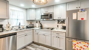A modern kitchen with white cabinetry, stainless steel appliances, and a 'happy host' towel on the refrigerator. - Near Hospital and Restaurants: Quiet & Relaxing (Waycross)