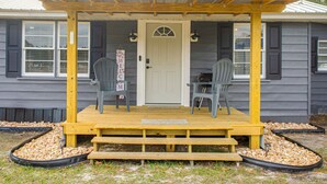 A wooden porch with two chairs and a table, a white door, and a welcome sign. - Near Hospital and Restaurants: Quiet & Relaxing (Waycross)