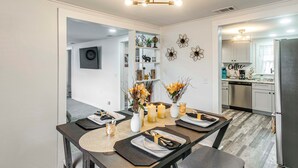 A modern kitchen with a built-in dishwasher, a coffee station, and a dining area with a table set for two. - Near Hospital and Restaurants: Quiet & Relaxing (Waycross)