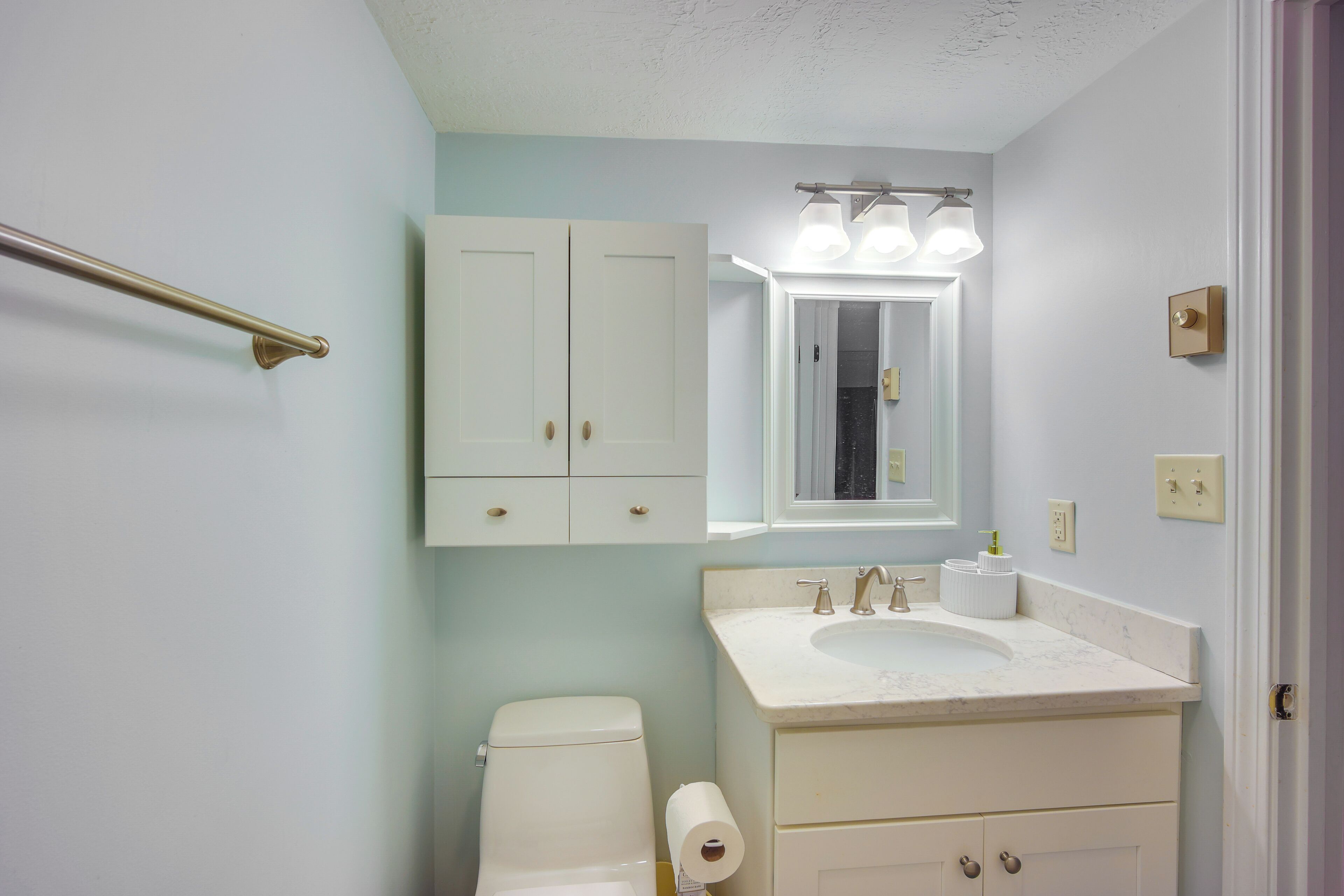 A bathroom with a toilet, sink, and cabinets.