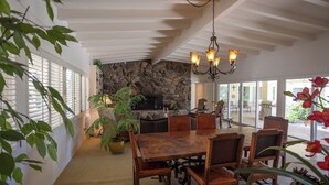 A dining area with a stone wall, wooden table, and chairs. - Poolside Splendor! Spacious De Anza Golf Club Home (Borrego Springs)