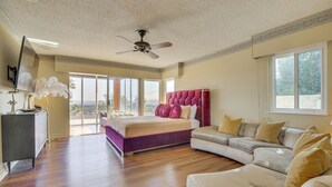 A spacious bedroom with a large bed, a sofa, and a ceiling fan. - Stunning MCM Escape w/ Mtn Views in San Bernardino (San Bernardino)