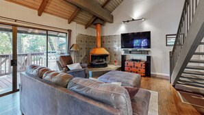 Ein gemütliches Wohnzimmer mit Kamin, Ledersofas, Fernseher und einer Holterrasse.