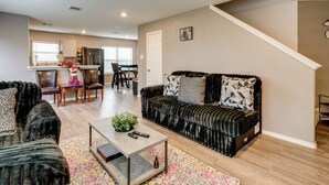 A modern living room with a black sofa, a coffee table, and a dining area with a table and chairs. - 2 Mi to Historic Dtwn Magnolia: Family Retreat (Magnolia)
