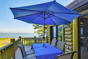 A wooden deck with a table and chairs under a blue umbrella, overlooking a body of water. - On-site Trails & Private Beach! Lake Huron Retreat (Harrisville)