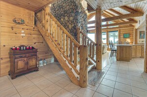 Un interior de madera con pared de piedra, escalera de madera y zona de cocina.