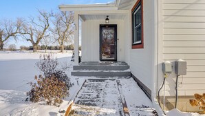 Une maison avec une porte d’entrée, des marches et une allée recouverte de neige.