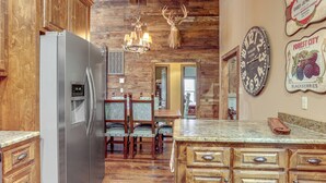 Eine Küche mit Holzausstattung, einem Edelstahl-Kühlschrank, einer Kandelaberleuchte und einem Hirschgeweih an der Wand.