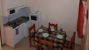 Ett kompakt kök med ett matbord, stolar och en mikrovågsugn.
