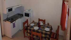 A compact kitchen with a dining table, chairs, and a microwave.