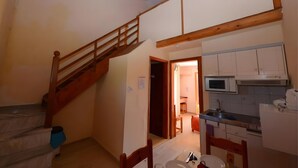 A kitchen with wooden beams, a dining area with chairs, a staircase, and a microwave.