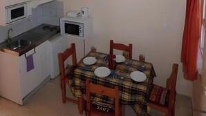 Une cuisine de taille réduite comprenant une table à manger, des chaises et un four à micro-ondes.