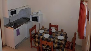 Une cuisine de taille réduite comprenant une table à manger, des chaises et un four à micro-ondes.