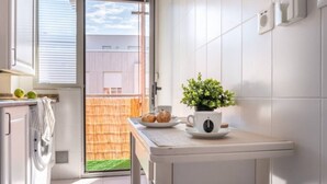 A modern kitchen with a sliding glass door leading to a balcony, a small table with a potted plant, and a cup of coffee. - San Roman apartment with private parking (Santander)