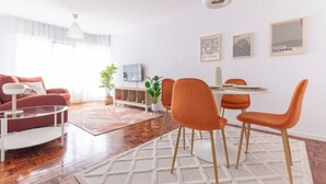 A modern living room with a sofa, coffee table, and orange chairs around a dining table. - San Roman apartment with private parking (Santander)