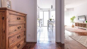 A spacious living area with a wooden dresser, a dining area with a chair, and a television on the wall. - San Roman apartment with private parking (Santander)